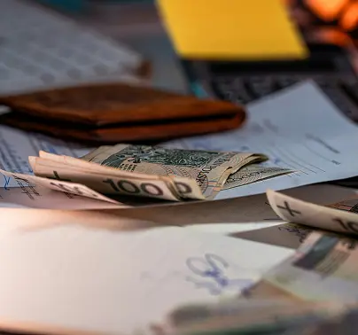 A wallet, dollar bills, signed papers, and documents scattered across a desk.