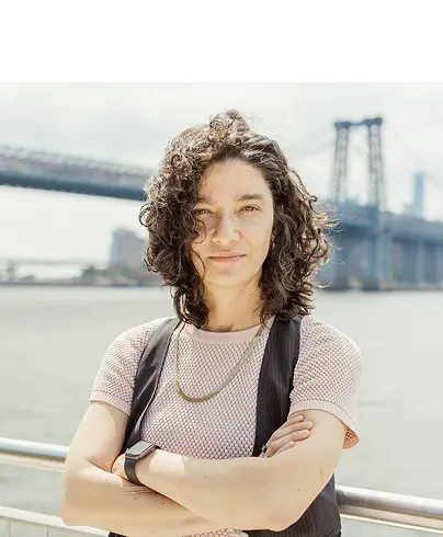 Lina Stillman standing outdoors with the Brooklyn Bridge visible in the background and the New York City skyline behind her. mobile version.