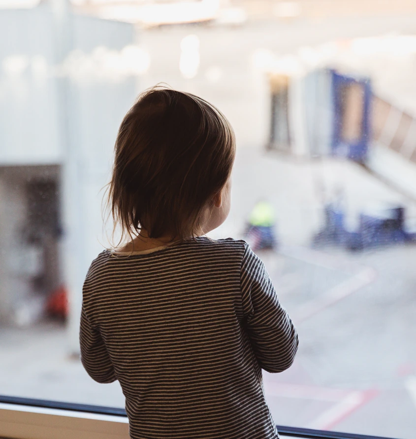 Child standing by a window and looking outside. The image accompanies content about Special Immigrant Juvenile Status (SIJS) and legal protections for immigrant youth.