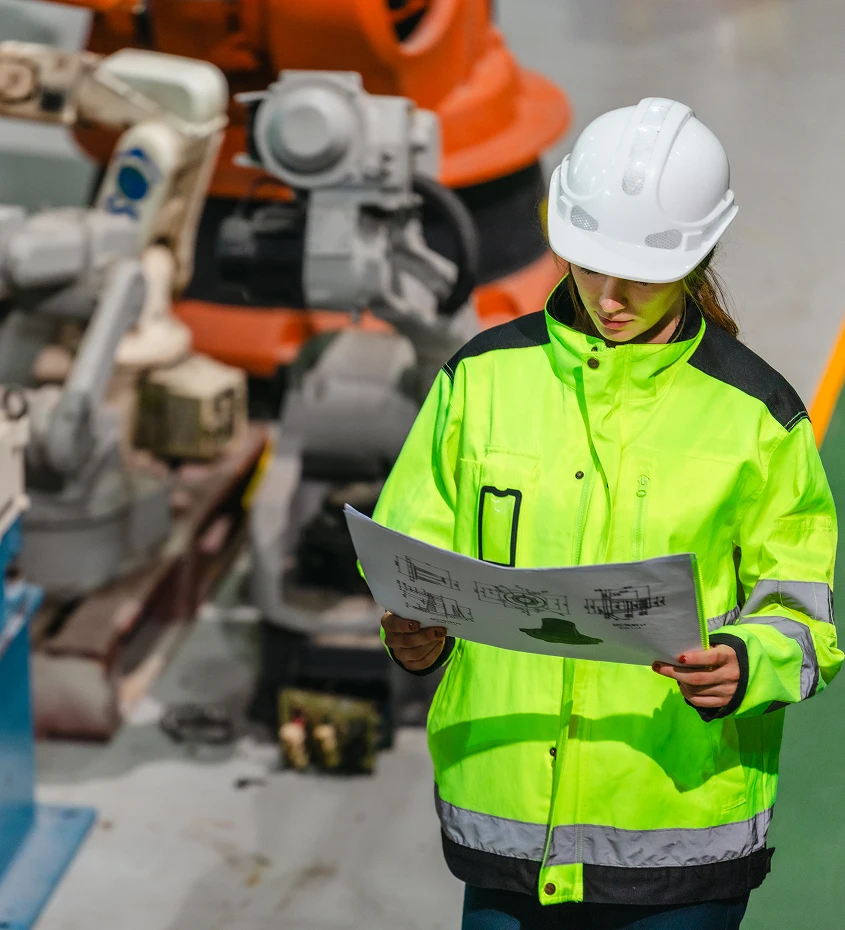 Engineer reviewing technical blueprints in an industrial setting, representing employment-based immigration for skilled workers.