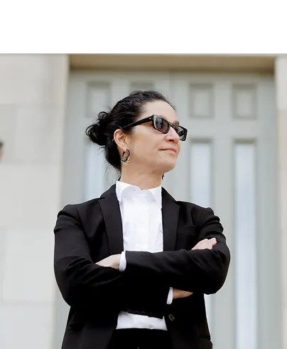 Lina Stillman standing with her arms crossed in front of the New York State Supreme Courthouse.